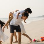 Asian young happy family enjoy vacation on beach in the evening. Dad, mom and kid relax playing together near sea when sunset while travel holiday. Lifestyle travel holiday vacation summer concept.